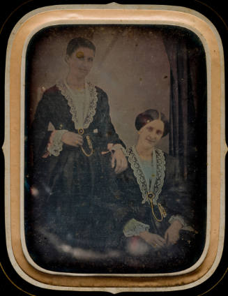 Two Women in Matching Dresses and Jewelry, One Seated