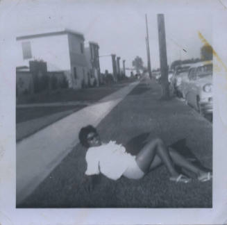 Untitled [Woman lays on lawn, leans back]