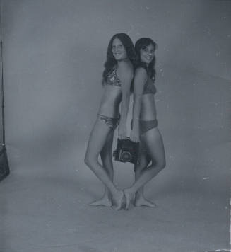 Untitled [Two women hold camera, stand back to back]