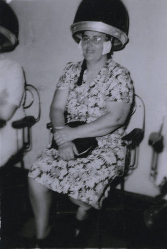 Untitled [Woman sits in beauty parlor chair]