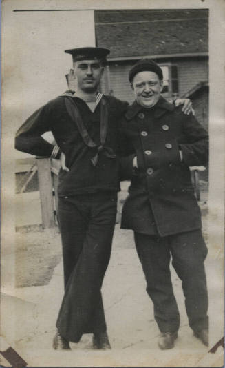 Untitled [Two men stand together, man on left wears uniform]