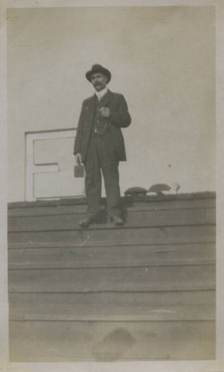 Untitled [Man stands on bleachers, holds camera]