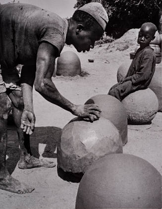 Nigeria, “In a small village near Jos a man mass produces by hand, huge earthenware pots by patting the clay with a stone over the moulds,”