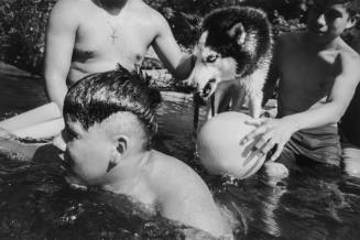 Young men playing with Huskie. The watering hole.