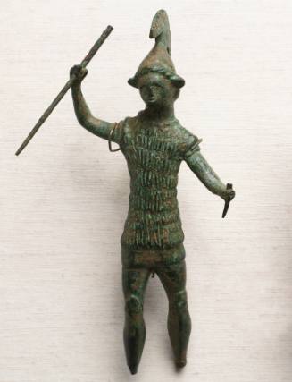 Warrior wearing incised fur cuirass over tunic, crested helmet, with spear in upraised right hand and dagger in left hand