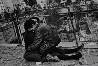 Untitled (Young couple sitting on cobblestone street)
