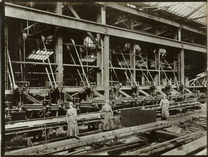 Women operating radial drilling machines, drilling holes in girders (from the British Ministry of Information photographs of women working in factories during WWI)