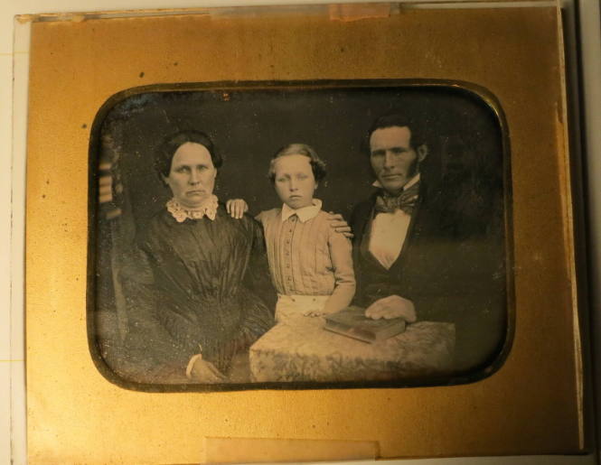 Seated Mother, Daughter, and Father with Book on Table