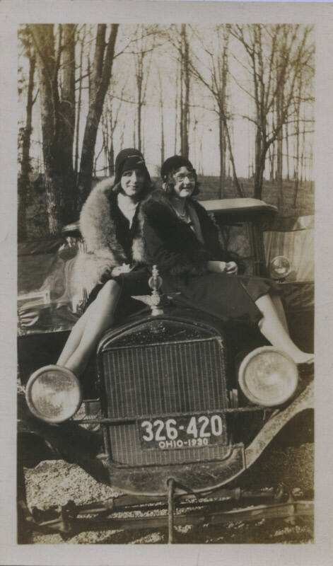 Untitled [Two women sit on car hood, whose plate reads 326-420 OHIO-1930]