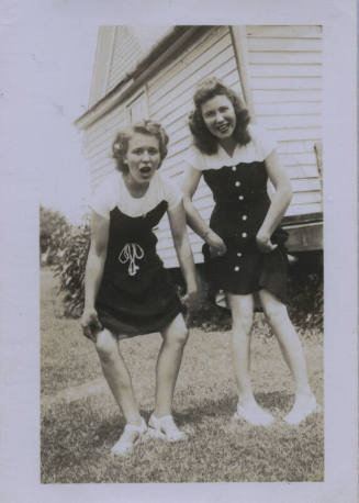 Untitled [Two women pull up skirts, reveal outward and inward facing knees respectively from left to right]