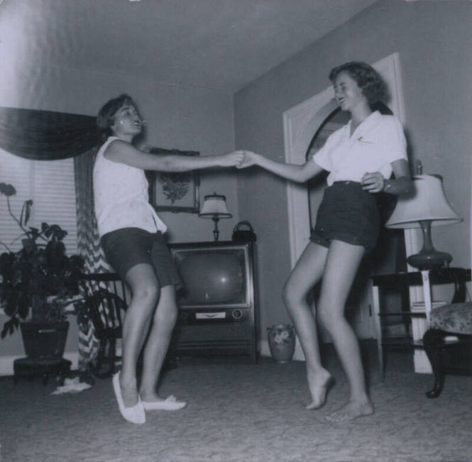 Untitled [Two women in light shirts and dark shorts dance holding each other's hand]