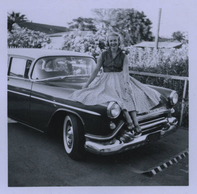 Untitled [Woman sits on car's hood, her patterned skirt spread out]
