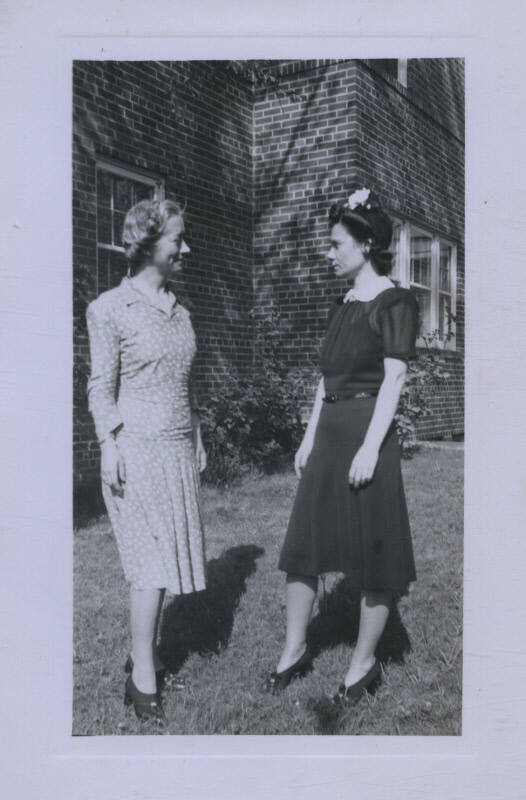 Untitled [Two women in profile facing each other outside a house]