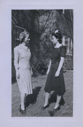 Untitled [Two women in profile facing each other outside a house]