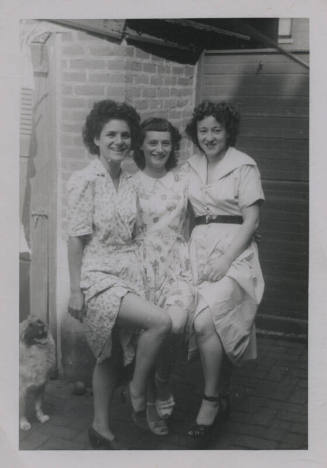 Untitled [Three women raise one knee to the center, dog in background]