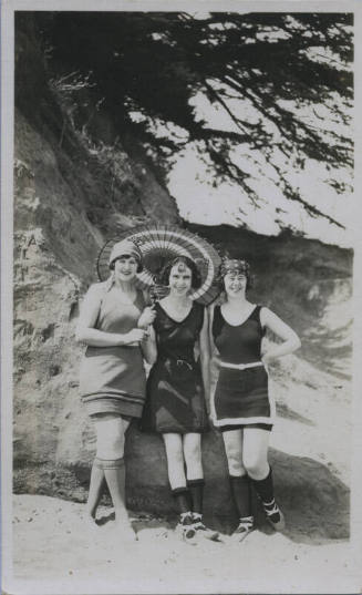 Untitled [Three women stand on a beach with umbrella, wear ballet slippers]