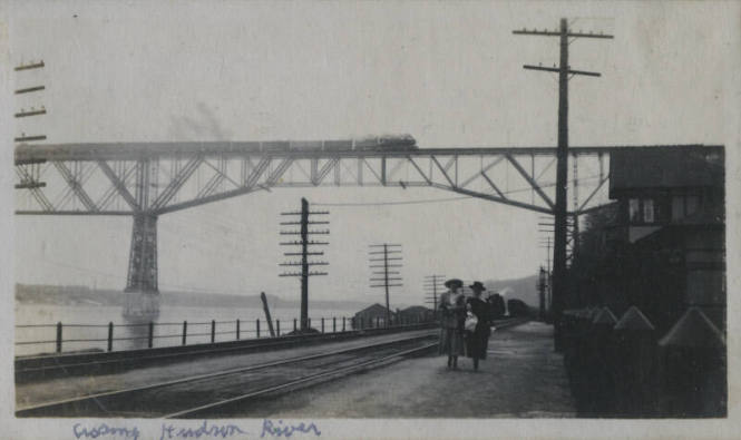 Untitled [Two people walk along Hudson, bridge in the background]