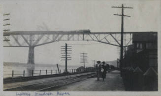 Untitled [Two people walk along Hudson, bridge in the background]