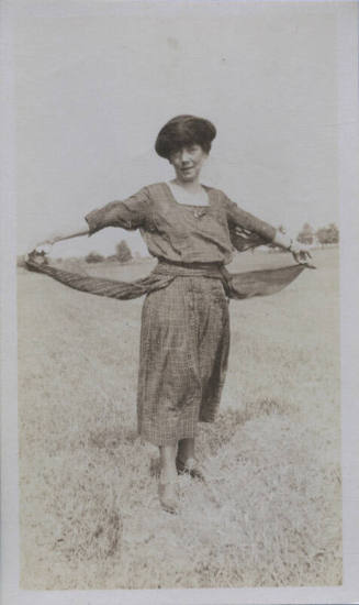 Untitled [Woman on field spreads out skirt on either side of her body]