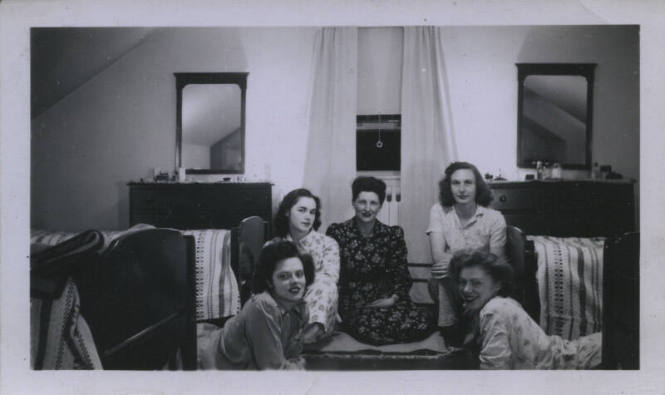Untitled [Five women sit on room floor, parallel mirrors in the background]