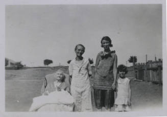 Untitled [Four women stand outside in horizontal line, seemingly oldest to youngest, left to right]