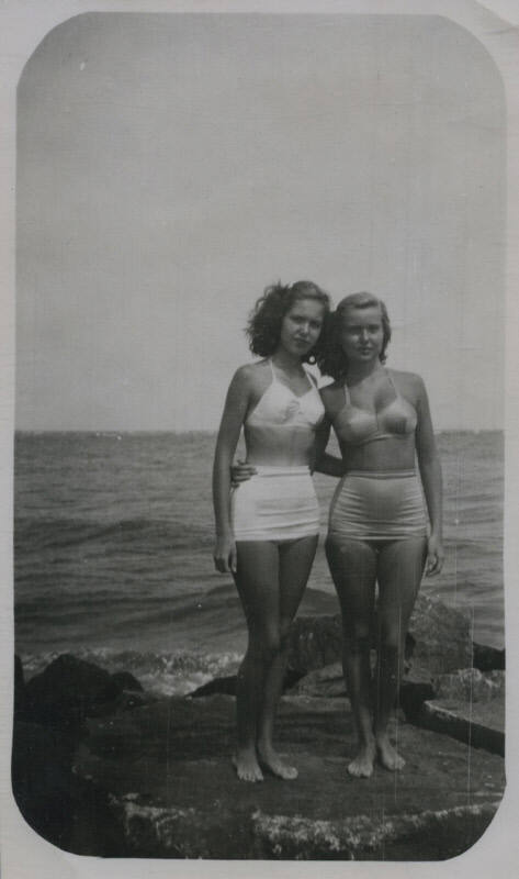 Untitled [Two women in bathing suits stand on a rock, the ocean in the background]