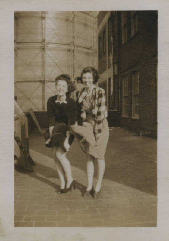 Untitled [Two women laugh and hold down skirts as wind blows them]