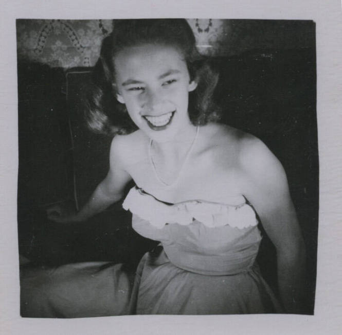 Untitled [Woman sits on couch and smiles widely]