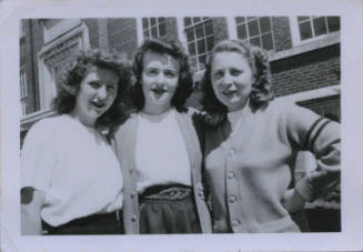 Untitled [Three girls in uniform stand side by side, building in background]