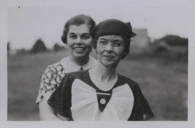 Untitled [Two women stand on a field, one in front of the other]