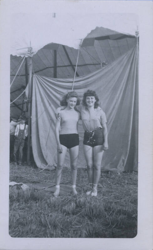 Untitled [Two women stand in front of a tent, boy in background]