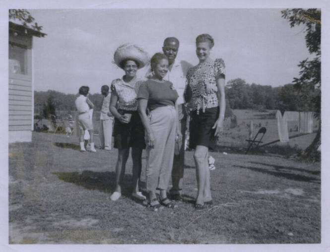 Untitled [Four people stand on a lawn, three people in the back row, one person in front]