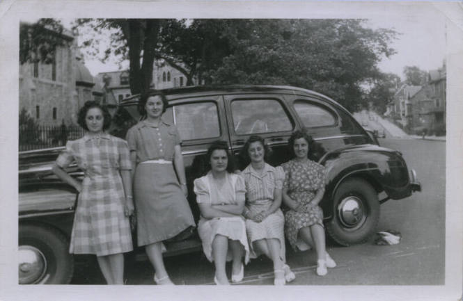 Untitled [Two women stand in front of car, three women sit on its side]
