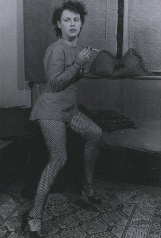 Untitled [Woman leans to one side, holds up cigarette with right hand]