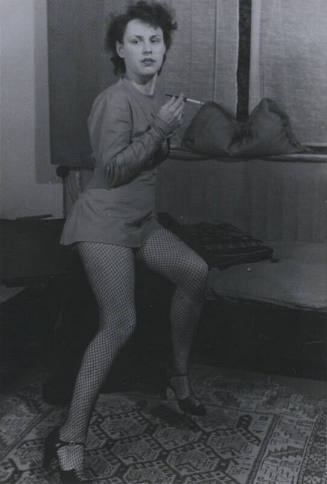 Untitled [Woman leans to one side, holds up cigarette with right hand]