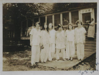 Untitled [Six women stand on porch, two women in background stand in house whose banner reads S?F (Sigma Delta Phi)]