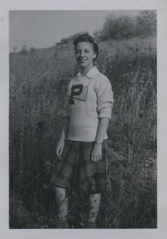 Untitled [Woman stands on field, wears sweater inscribed with letter P]