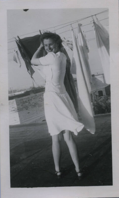 Untitled [Woman looks over shoulder, hangs clothes]