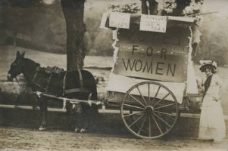 Untitled [Subject stands behind coach that reads VOTES FOR WOMEN]
