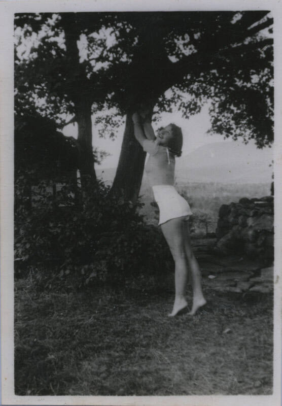 Untitled [Woman stands on tips of toes, reaches out to tree branch]