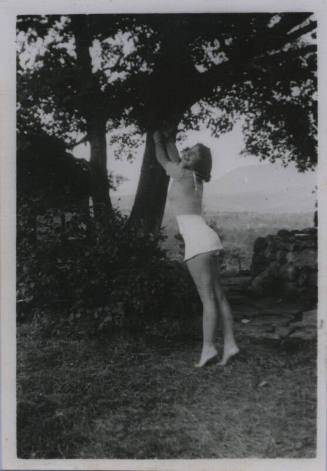 Untitled [Woman stands on tips of toes, reaches out to tree branch]