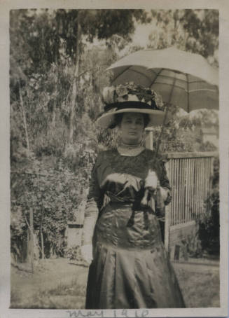 Untitled [Woman stands in garden, holds umbrella]