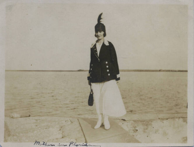 Untitled [Woman stands on ledge, body of water in background]