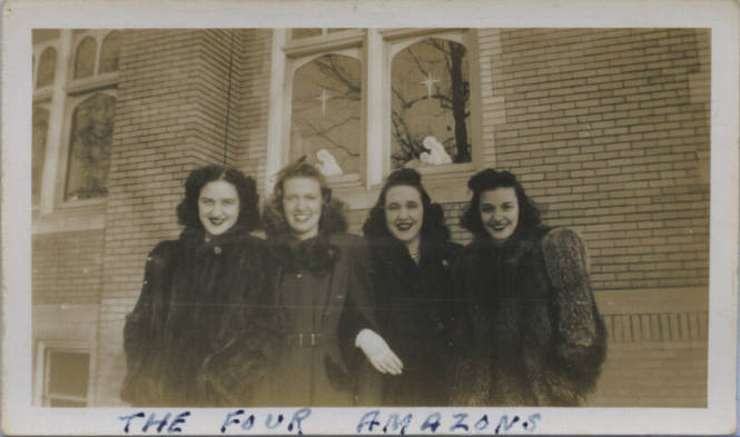 Untitled [Four women stand outside building, religious motifs in background windows]