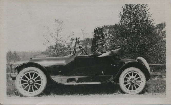 Untitled [Woman sits in car's driver's seat, looks sideways to face camera]