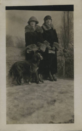 Untitled [Two women stand on snowy field, dog in foreground]