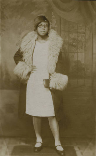 Untitled [Woman stands, hands on waist, living room wallpaper in background]