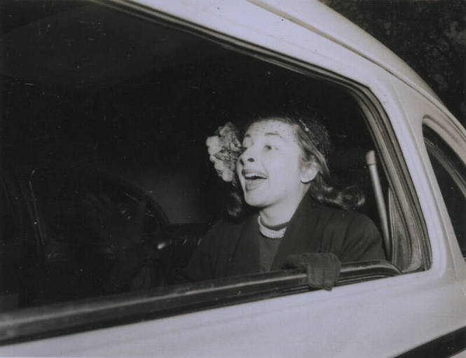Untitled [Woman sits on car's backseat, seemingly enunciating'