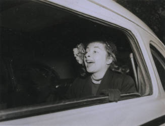 Untitled [Woman sits on car's backseat, seemingly enunciating'