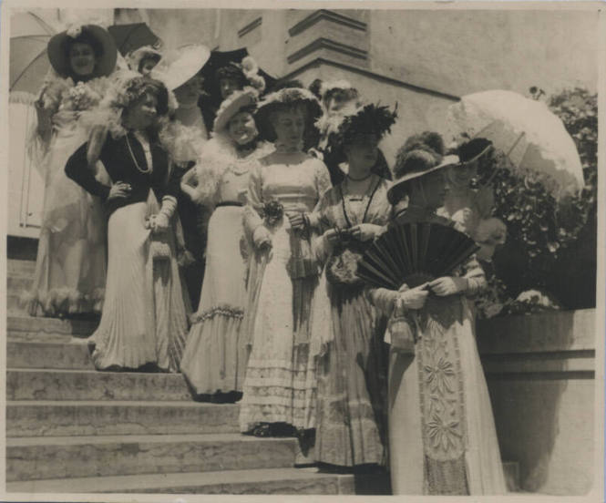 Untitled [Eleven women stand on steps of stairs, wear hats and long embroidered dresses]